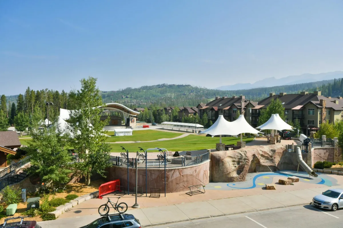 This image captures an outdoor concert stage set against a mountain backdrop, with large white tents, landscaped grounds, a play area for children, and visible attendees engaging in community events. The festive atmosphere and scenic environment directly evoke the lively events and concerts described in the section, especially those at Hideaway Park and Rendezvous Event Center.